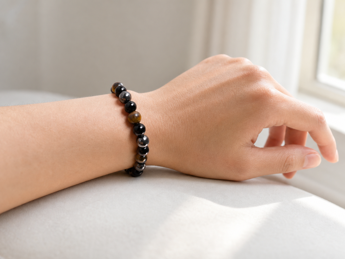 Which hand to wear tiger eye bracelet for female styling, shown with a mixed tiger eye, black obsidian and hematite bracelet on one wrist.