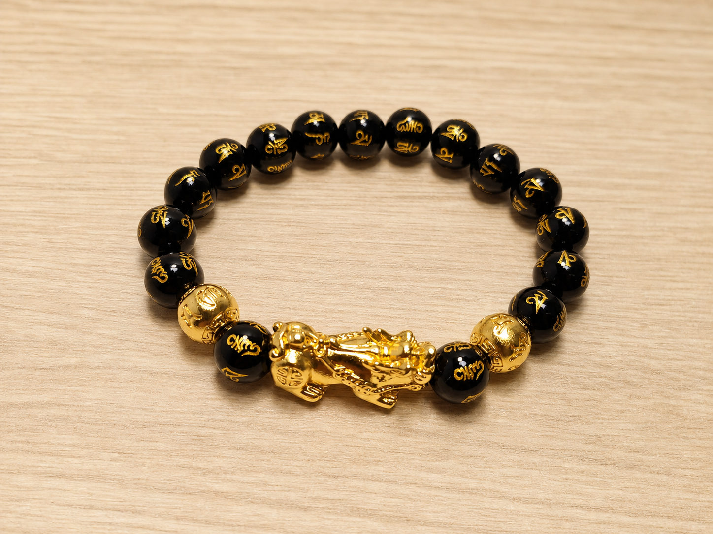 Pixiu black obsidian bracelet shown on a neutral wooden surface.