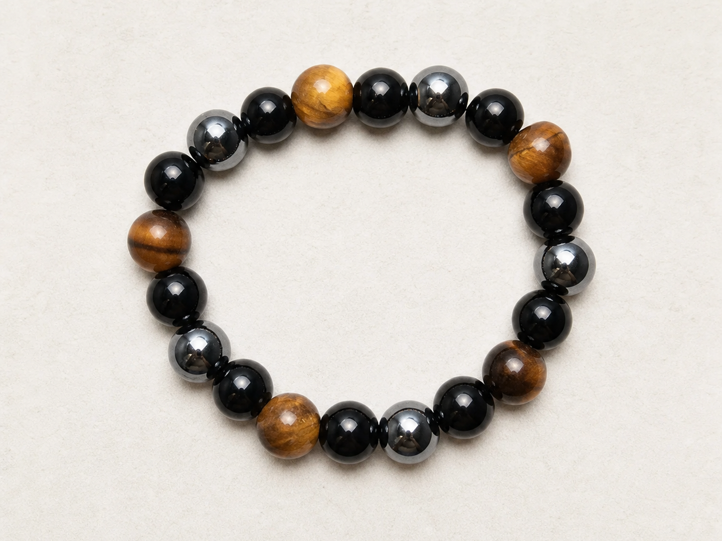 Top view of a mixed hematite, tiger eye and black obsidian bracelet showing its circular structure.