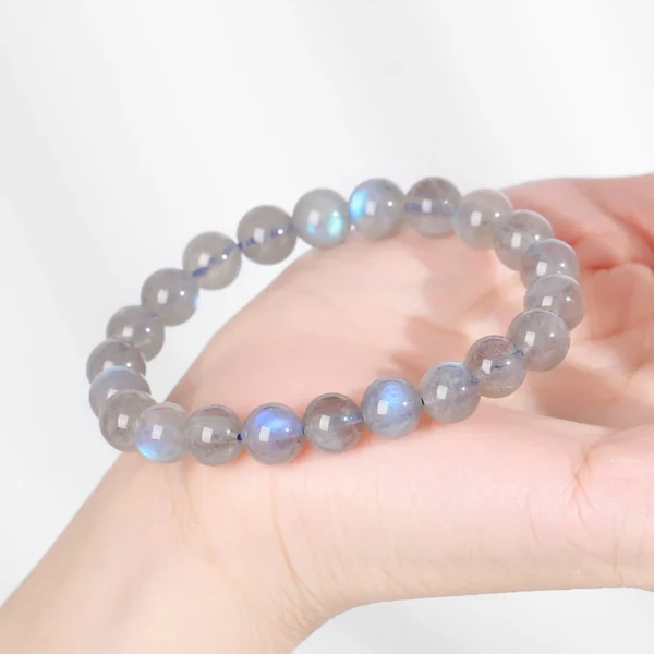 Gray moonstone bead bracelet held in hand under bright light