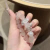 Rose quartz and white phantom quartz bracelet held in hand
