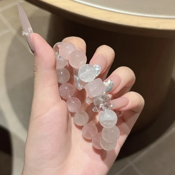 Rose quartz and white phantom quartz bracelet held in hand