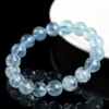 Single-strand aquamarine bead bracelet beside a white display stand
