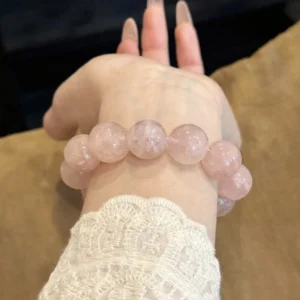 Close view of a pale pink 14mm rose quartz bracelet on the wrist